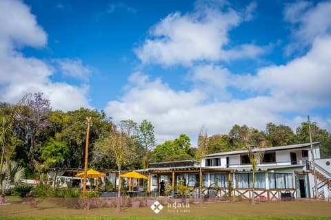Vista geral da Chácara Primeiro de Maio com jardim, pergolados e edificação principal sob céu azul